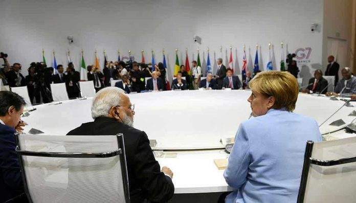 1970862773 People seated around a large round table, flags behind.