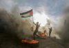 Infant Killed, Evidence Goes Missing Protester waves a Palestinian flag amid smoke and fire
