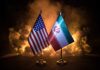 Uranium Fight Could Torpedo ‘Peace’ Deal Flags of the United States and Iran displayed on stands with a smoky background