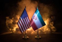 Uranium Fight Could Torpedo ‘Peace’ Deal Flags of the United States and Iran displayed on stands with a smoky background