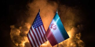 Uranium Fight Could Torpedo ‘Peace’ Deal Flags of the United States and Iran displayed on stands with a smoky background