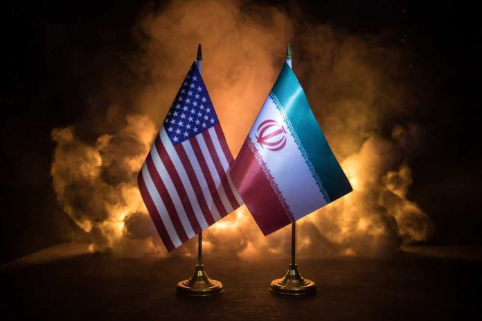 shutterstock_1986616796 Flags of the United States and Iran displayed on stands with a smoky background