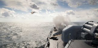 U.S. Strikes Inside Iran—Not Over Naval ship firing a cannon with a fighter jet flying overhead