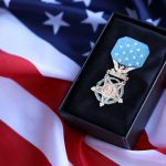 A military medal displayed on a black box with an American flag background