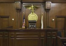 Six Months For Child Rape?! Judges bench in an empty courtroom, scales emblem above.