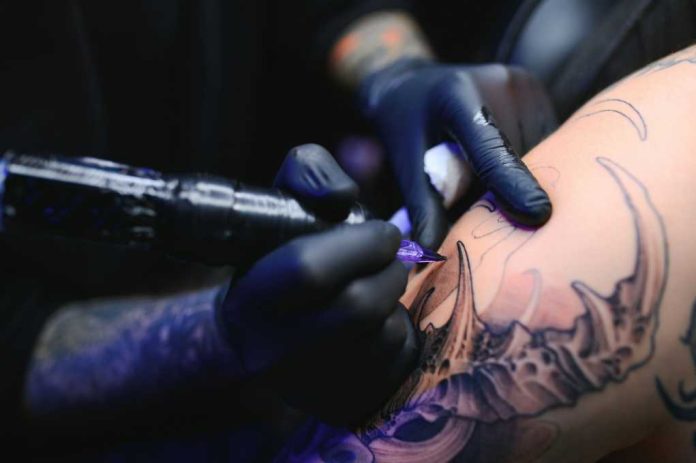 professional-tattoo-master-introduces2459389949jpg Tattoo artist with black gloves inking a detailed arm design