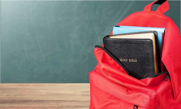 shutterstock_1183389583 Red backpack with books on a classroom desk
