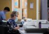 Court Smacks Down USPS Ballot Gatekeeping Election workers wearing masks process mail-in ballots at tables