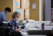 Court Smacks Down USPS Ballot Gatekeeping Election workers wearing masks process mail-in ballots at tables