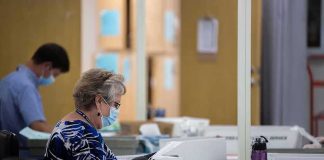 Court Smacks Down USPS Ballot Gatekeeping Election workers wearing masks process mail-in ballots at tables