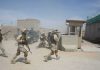 Iranian Missiles Kill Americans Soldiers in desert uniforms run past a checkpoint amid dust