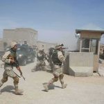 Iranian Missiles Kill Americans Soldiers in desert uniforms run past a checkpoint amid dust
