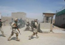 Iranian Missiles Kill Americans Soldiers in desert uniforms run past a checkpoint amid dust