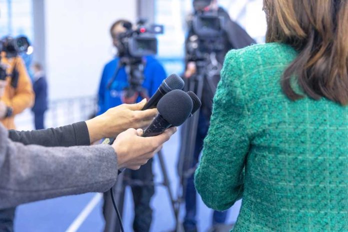 shutterstock_2081472568 Hands holding microphones in front of a person at a press conference