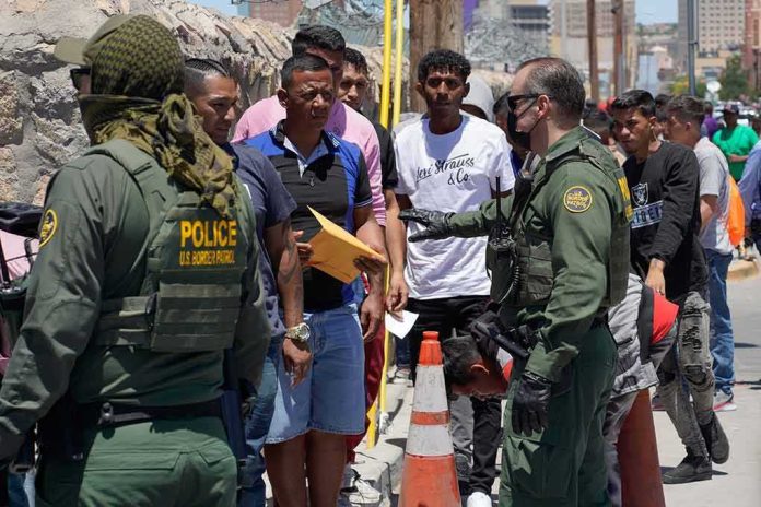 shutterstock_2300859029 Border patrol officers speak with a line of people outdoors