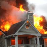 House engulfed in flames with heavy smoke from the roof