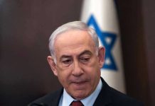 Is Iran Targeting Netanyahu’s SON?! Man in suit with Israeli flag in background.