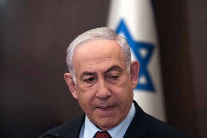2415917203 Man in suit with Israeli flag in background.