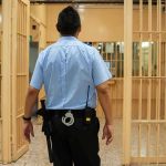 50 Police Chiefs Unite Against Early Release of Criminals corrections officer walking through prison corridor