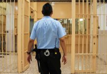 50 Police Chiefs Unite Against Early Release of Criminals corrections officer walking through prison corridor