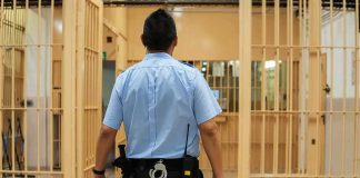 50 Police Chiefs Unite Against Early Release of Criminals corrections officer walking through prison corridor