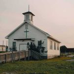 Church Turned Kill Zone — Dozens Vanish Small white church with steeple and cross at sunset