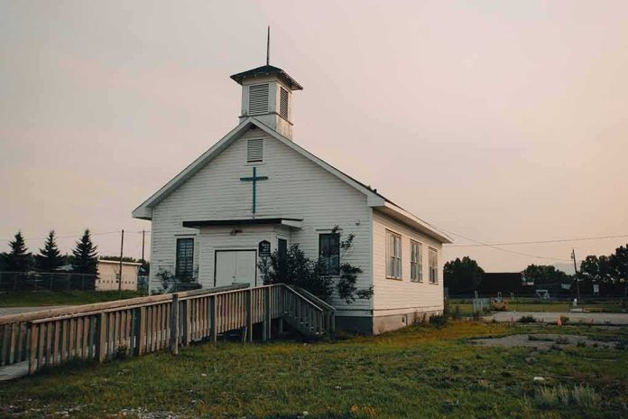 shutterstock_2342897857 Small white church with steeple and cross at sunset
