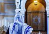 Man Attacks Jewish Worshippers Inside NYC Synagogue Person in white and blue prayer shawl facing ornate interior