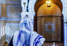 Man Attacks Jewish Worshippers Inside NYC Synagogue Person in white and blue prayer shawl facing ornate interior