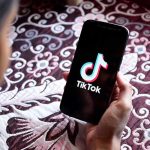 TikTok Cruelty Costs Six-Figure Job Hand holding phone showing TikTok logo.
