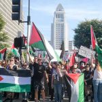 Protesters holding Palestinian flags gather in a city street