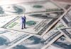Country Just Assigned Billionaires Their Own Tax Watchers Miniature businessman standing on US dollar bills