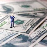 Country Just Assigned Billionaires Their Own Tax Watchers Miniature businessman standing on US dollar bills