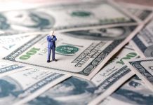Country Just Assigned Billionaires Their Own Tax Watchers Miniature businessman standing on US dollar bills