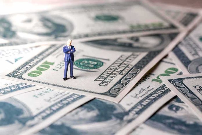 shutterstock_1064329202 Miniature businessman standing on US dollar bills