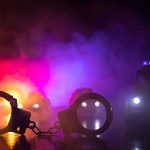 Mayor SLAMS Police, Keeps Own Security! Handcuffs on a surface with police cars and flashing lights in smoky darkness
