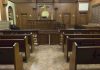 State Takes Catholic Teen to ‘Transition’ Her Interior view of an empty courtroom with wooden benches and a judges bench