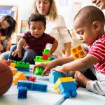 Senator Torches Trump Vaccine Flip Karyn Polito with toddlers building blocks on a play mat
