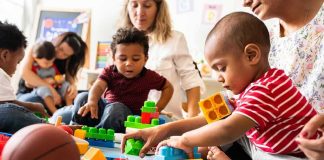 Karyn Polito with toddlers building blocks on a play mat