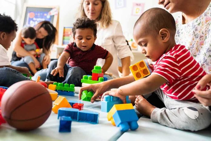 Karyn Polito with toddlers building blocks on a play mat