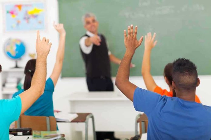shutterstock_141891325-3 Students raising hands in a classroom while teacher points
