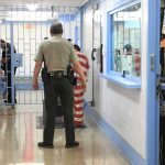 Federal Jail MELTDOWN Triggers Mass Exodus Corrections officers escort an inmate in a jail hallway
