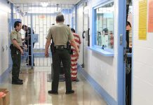 Federal Jail MELTDOWN Triggers Mass Exodus Corrections officers escort an inmate in a jail hallway