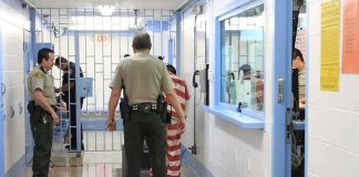 Federal Jail MELTDOWN Triggers Mass Exodus Corrections officers escort an inmate in a jail hallway