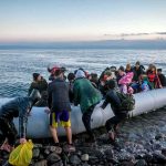 Nigel Farage Stokes Iran Infiltration Furor People arriving in a crowded inflatable boat at a rocky shore