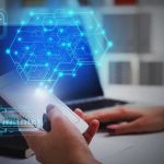 Apple Bends To China — What’s The Catch? Hands using smartphone near laptop with digital hexagon interface overlay