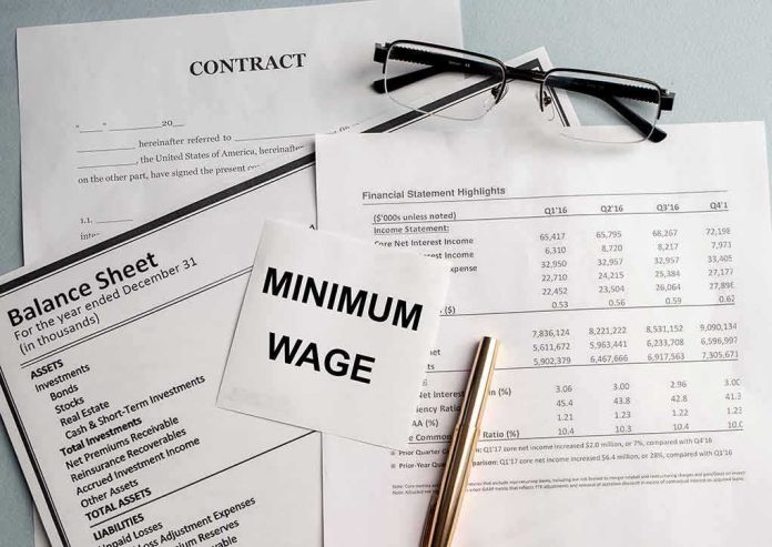 Minimum wage note on financial documents with glasses and pen