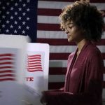 Violent Woman Claims Upend Maine Race Voter at a polling booth with an American flag backdrop
