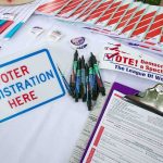 The Question Nobody’s Actually Answering About Voter ID Voter registration table with forms, pens, and informational materials