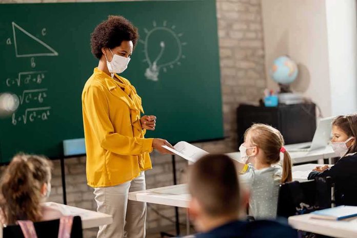 shutterstock_1798363270 Teacher in yellow shirt handing paper to student in classroom